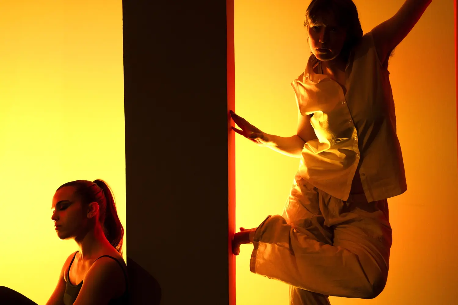 Two performers moving through warm stage light