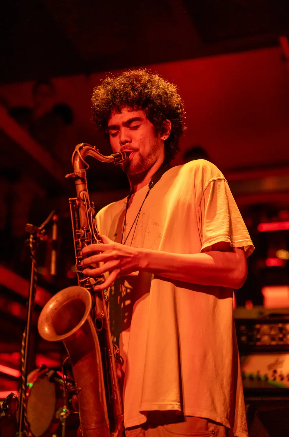 A young saxophonist performing under red light