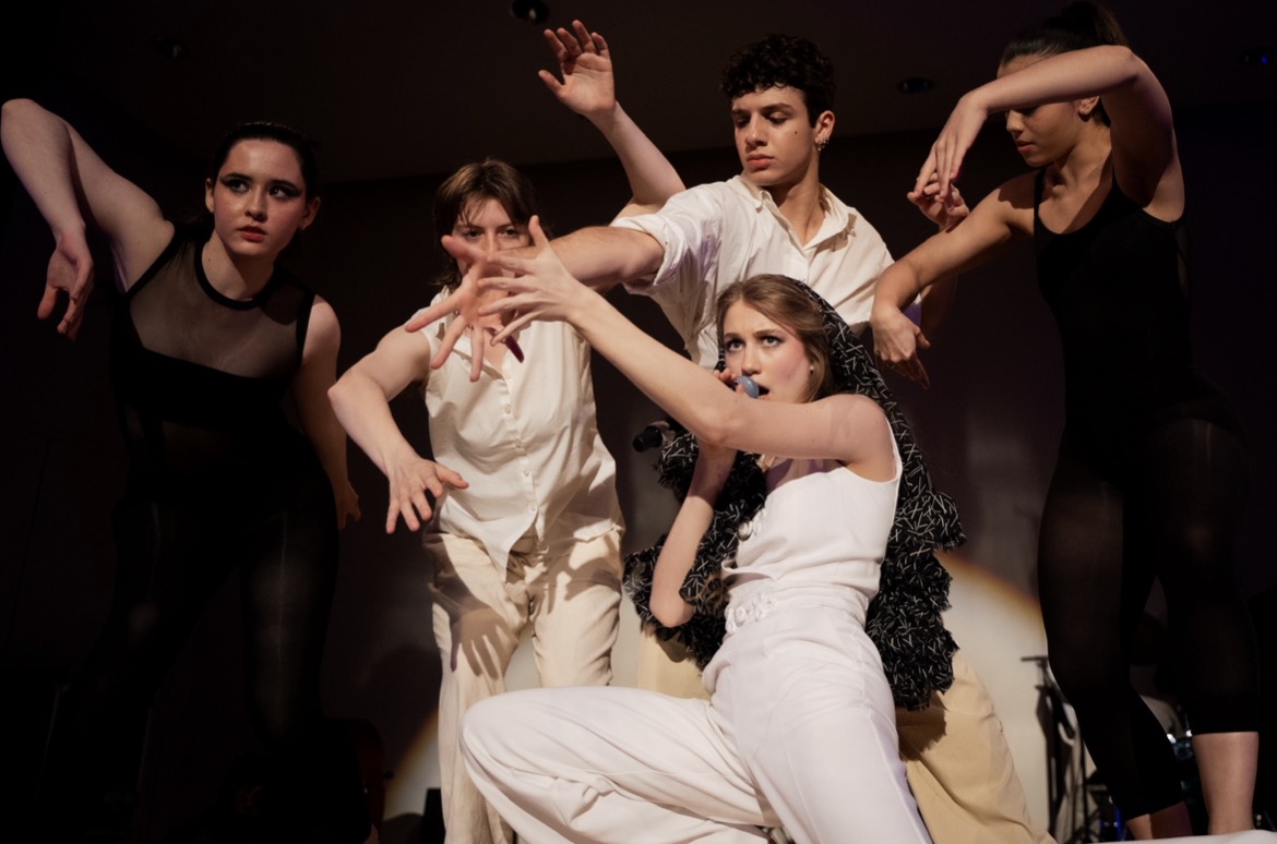 Young performers surrounding a singer onstage